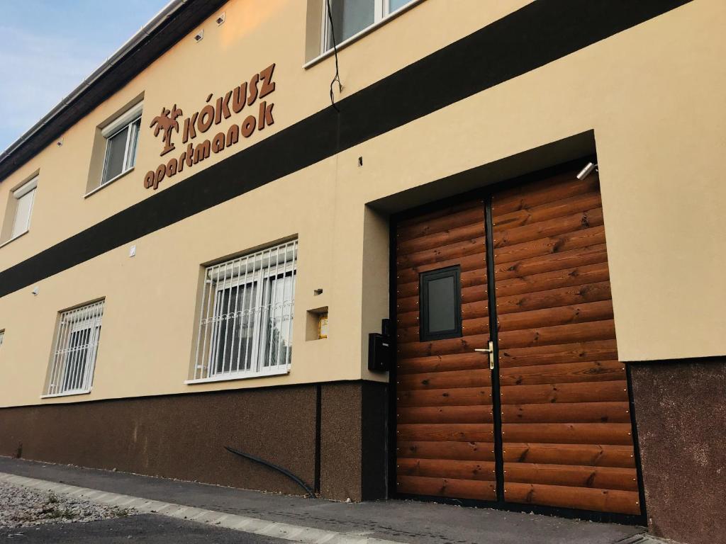 un edificio con una puerta de garaje de madera en la parte delantera en Kókusz Apartmanok, en Eger