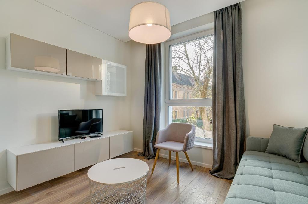 ein Wohnzimmer mit einem Sofa, einem TV und einem Fenster in der Unterkunft City Studio 1A - Courtyard View in Vilnius