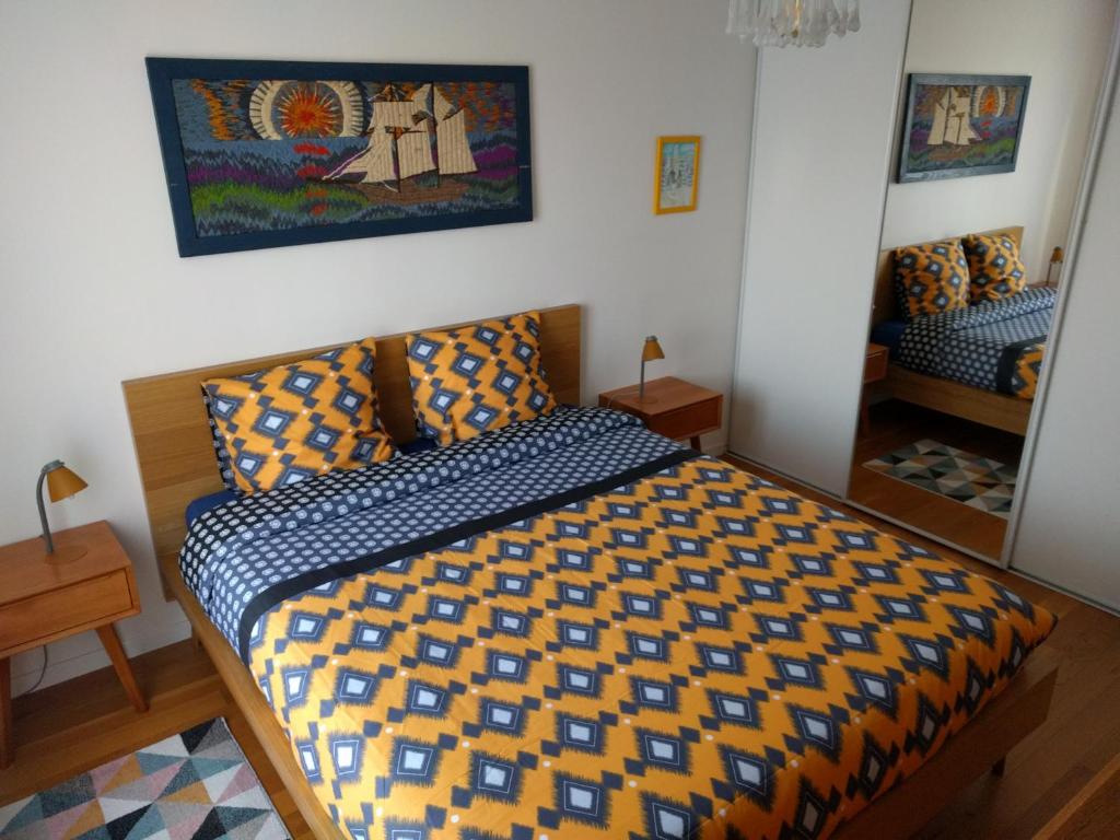a bedroom with a bed with a yellow and blue comforter at L'Orée de Versailles in Versailles