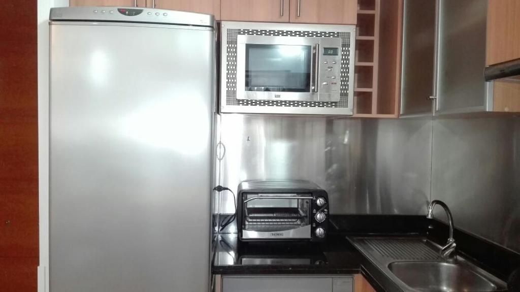 a kitchen with a refrigerator and a microwave at Austral Rentahome Américo Vespucio Norte in Santiago
