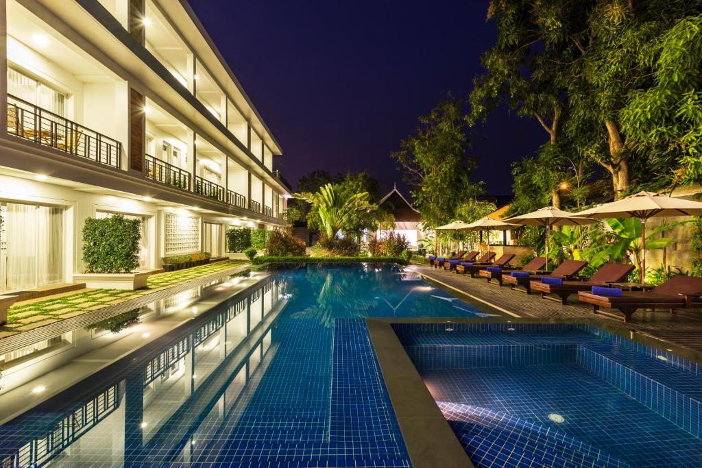 a swimming pool in front of a building at night at Malenne d'Angkor Residence in Siem Reap