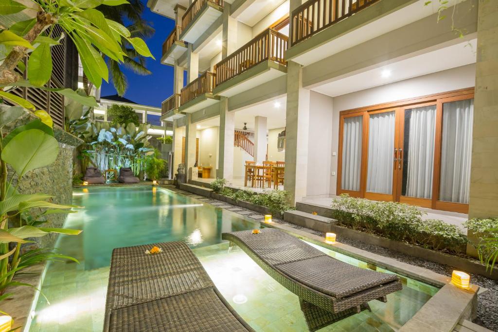 烏布的住宿－畢瑪烏瑪拉旅館，一个带长椅的房子中间的游泳池
