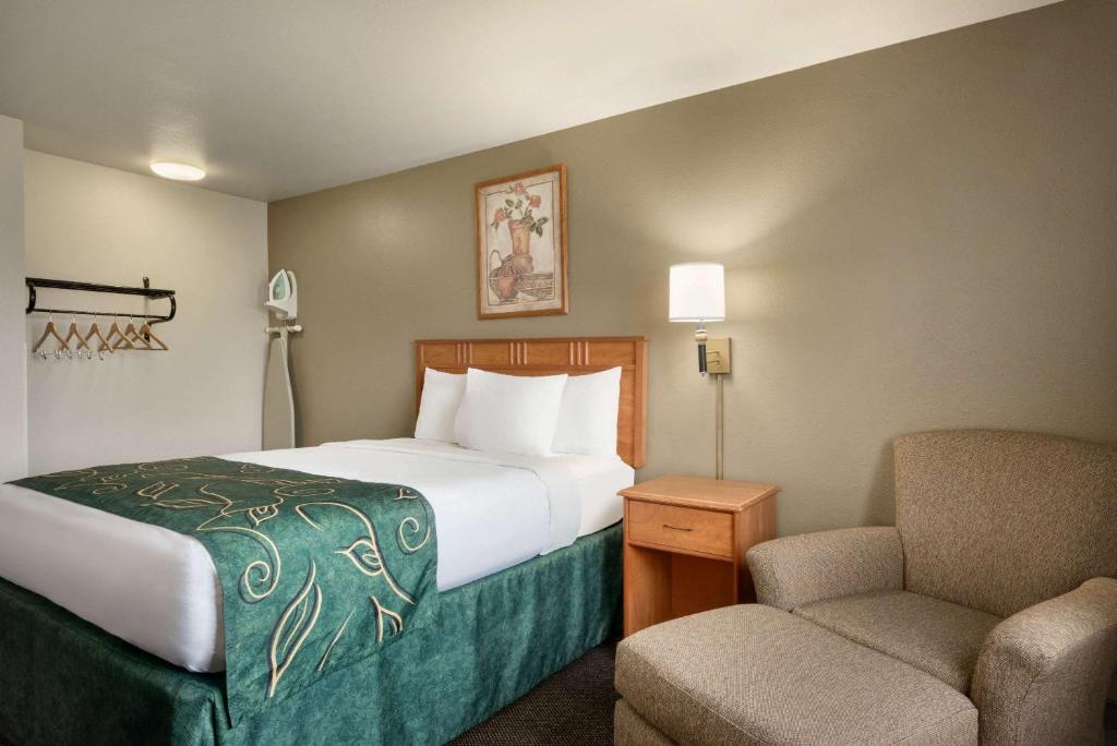 a hotel room with a bed and a chair at Travelodge by Wyndham Missouri Valley in Missouri Valley