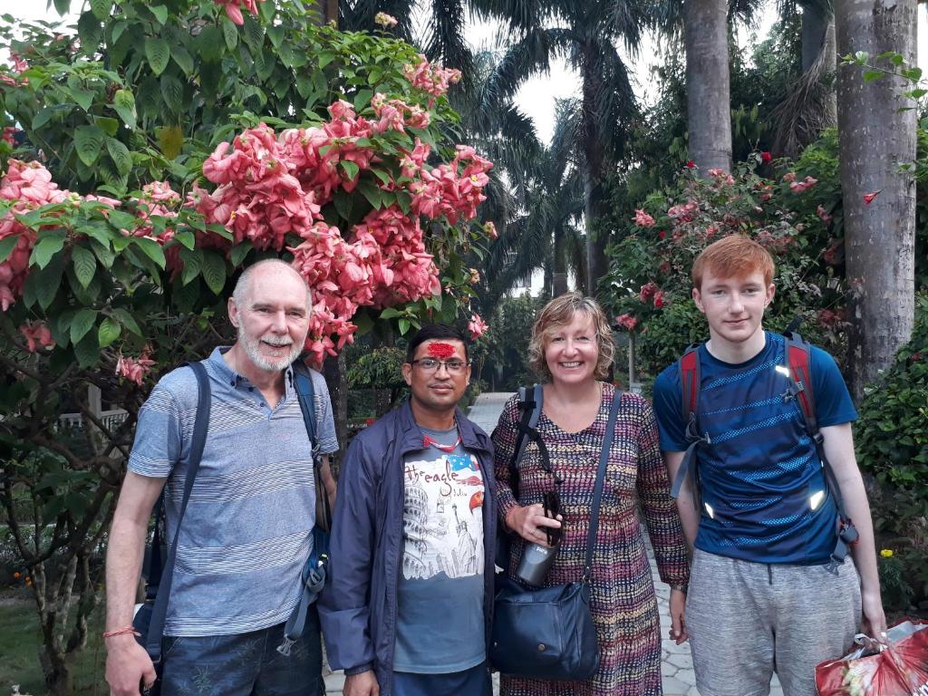 a family posing for a picture in front of flowers at Sauraha Resort in Sauraha