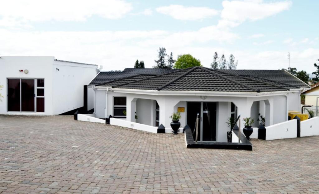 a white house with a brick driveway at Shoes Guest House in Mthatha