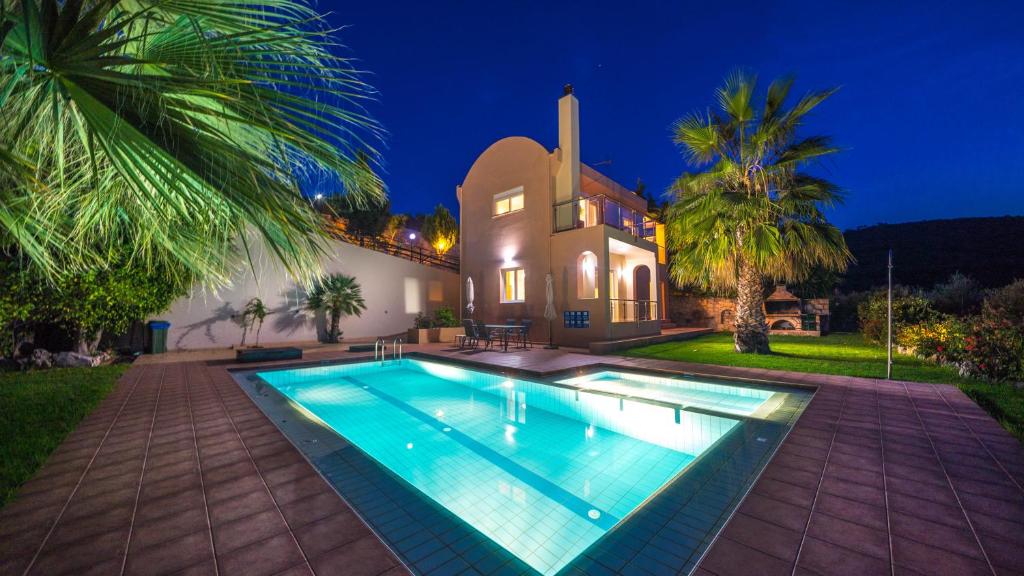 a villa with a swimming pool in front of a house at Meliades Villas in Agia Marina Nea Kydonias