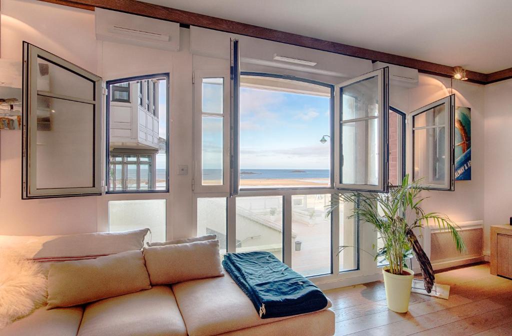- un salon avec un canapé et une vue sur l'océan dans l'établissement Le Grand Sillon - Le Georges, à Saint-Malo