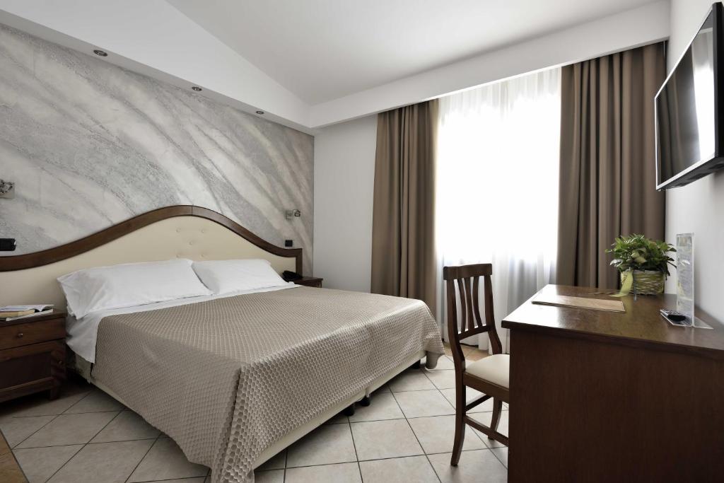 a hotel room with a bed and a desk and a television at Hotel Nicoletta in Santa Maria Navarrese