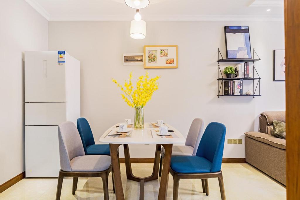 a dining room table with blue chairs and a vase of flowers at Chongqing Yubei·Chongqing North Railway Station· Locals Apartment 00138340 in Chongqing
