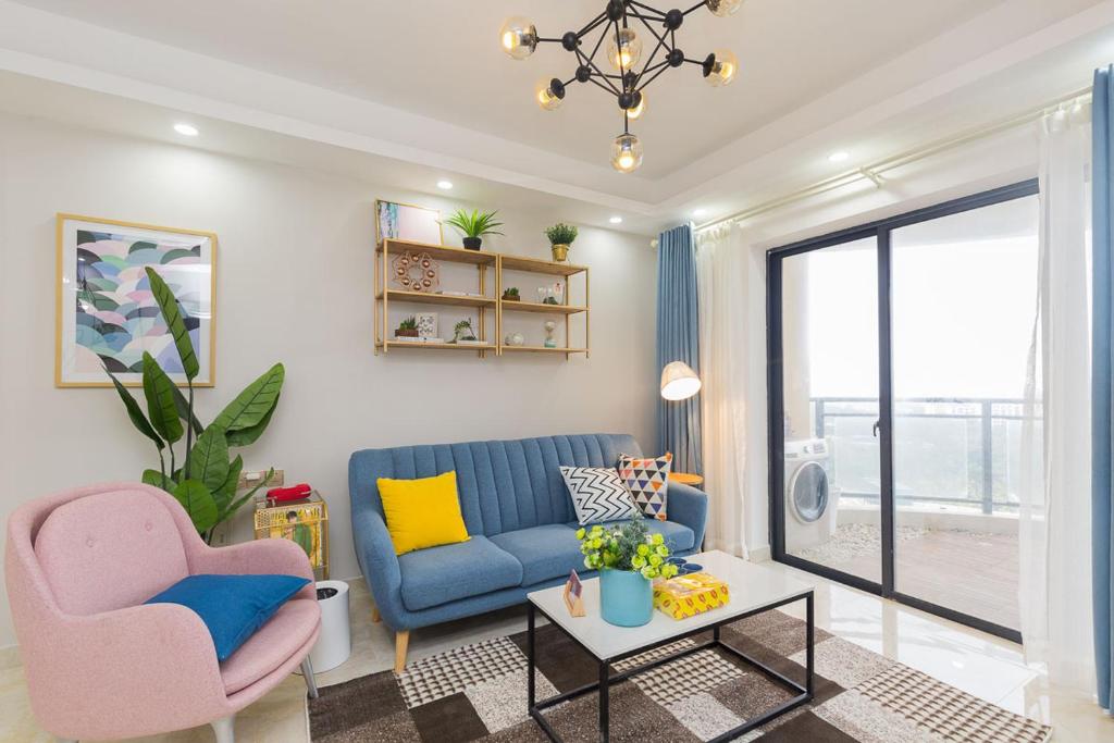 uma sala de estar com um sofá azul e duas cadeiras em Haikou Meilan·Hainan Univeristy· Locals Apartment 00138360 em Haikou