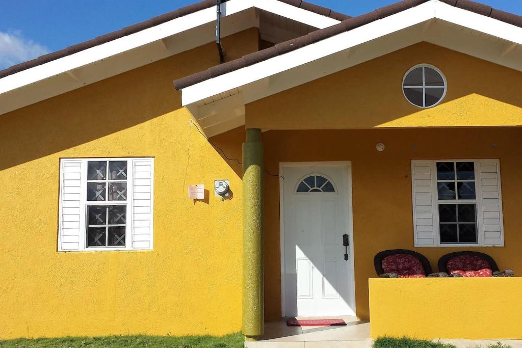 a yellow house with a white door and windows at Josan's Haven in Ocho Rios