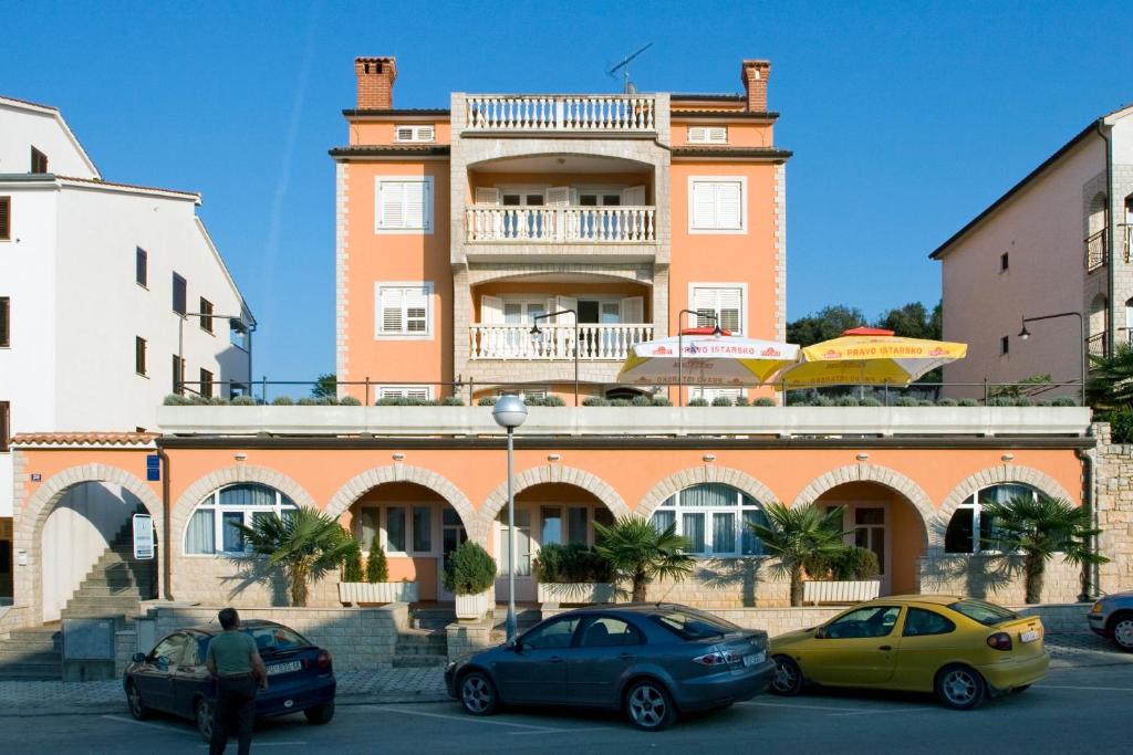 un edificio con auto parcheggiate di fronte di Apartments Valentino a Vrsar
