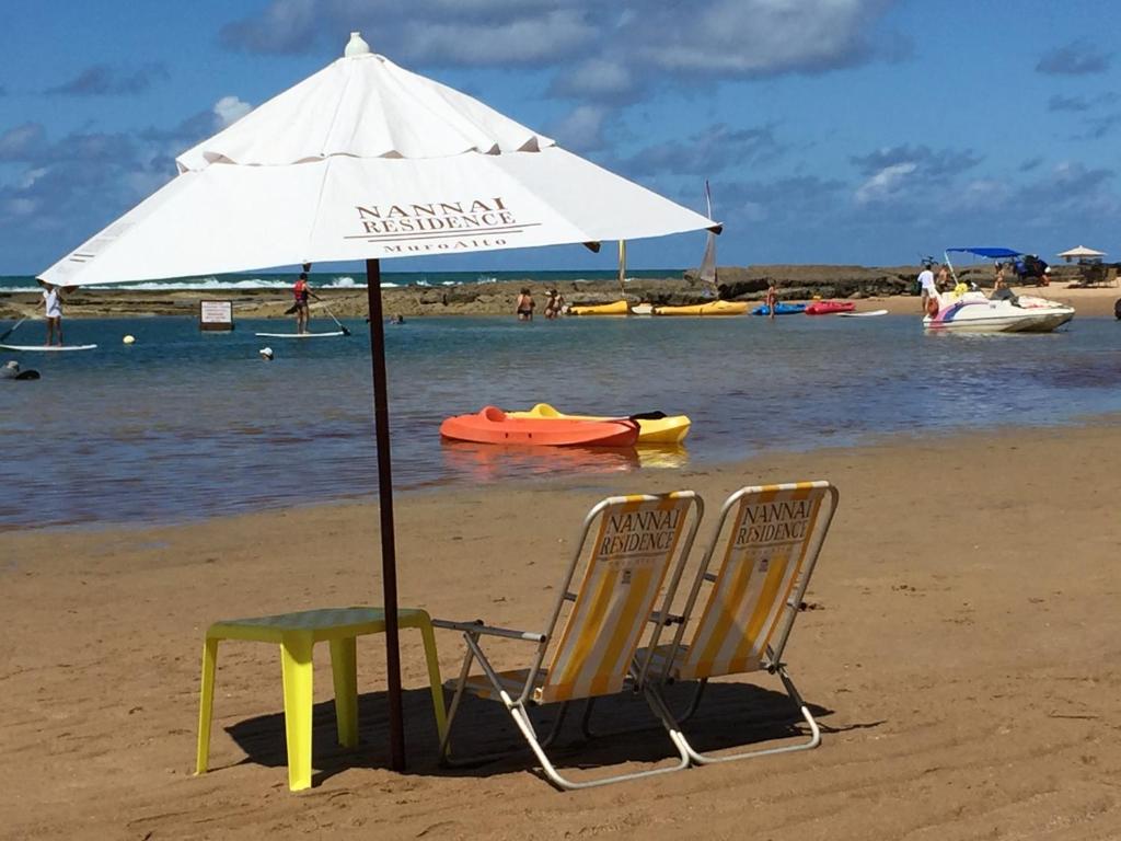 two chairs and an umbrella on the beach at Nannai Térreo Porto de Galinhas 06 in Porto De Galinhas