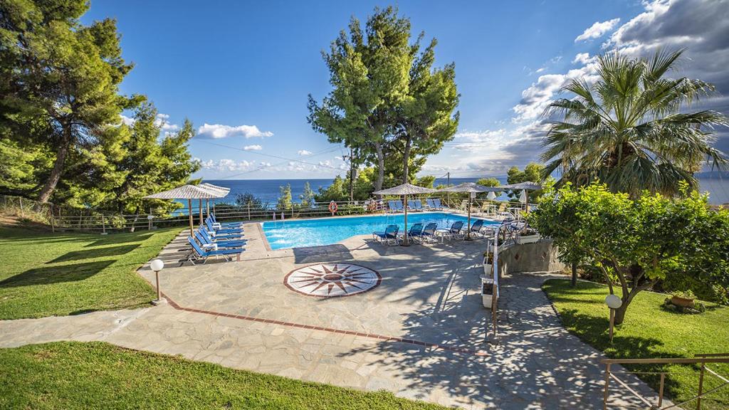 a pool with chairs and umbrellas and the ocean at Thea Hotel in Possidi