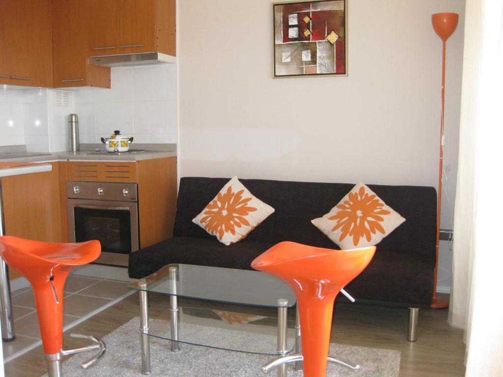 sala de estar con sofá y 2 sillas de color naranja en Barcelo Suites Viña del Mar, en Viña del Mar