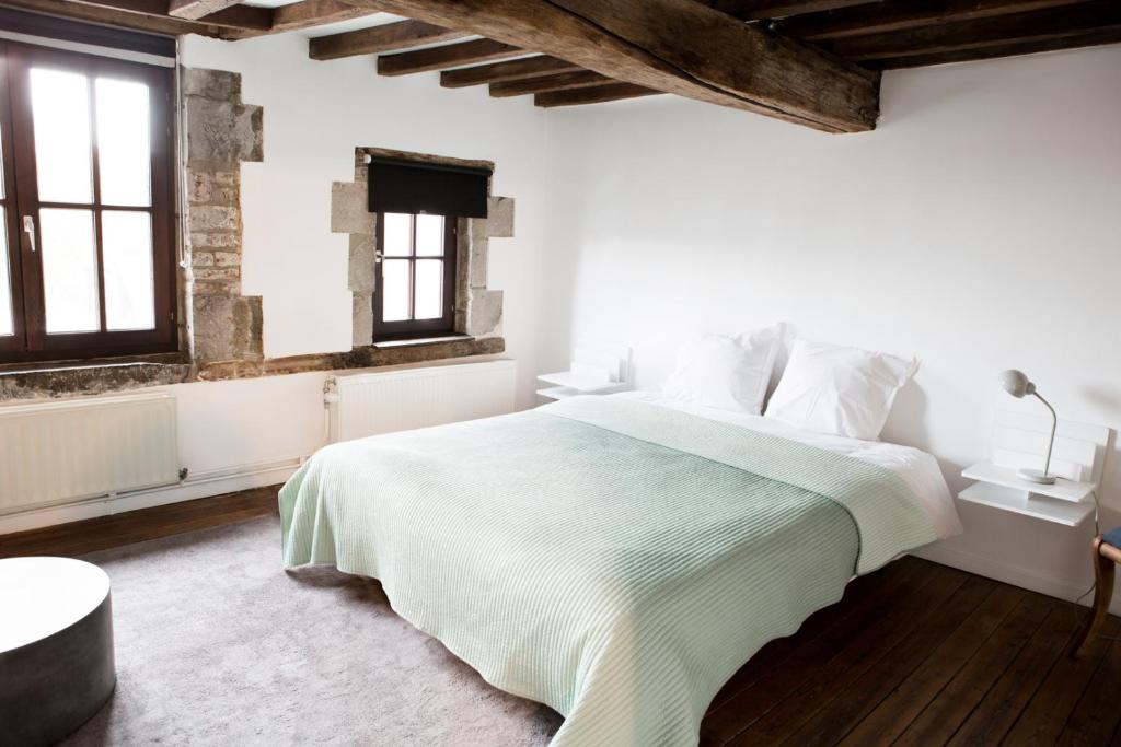 biała sypialnia z dużym łóżkiem i oknami w obiekcie Maison Sainte-Marguerite w mieście Liège