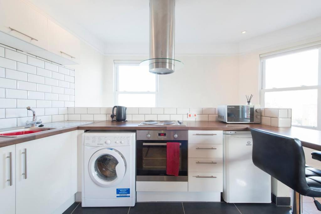 a white kitchen with a washing machine and a sink at Leckhampton Road Apartments - Cheltenham in Cheltenham