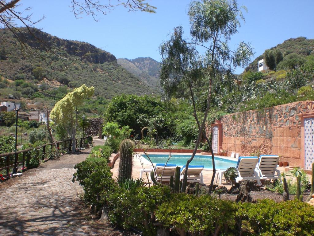 a swimming pool with lounge chairs and a mountain at Casa Vacacional Rural Villa Barranco de los Cernícalos in Valsequillo