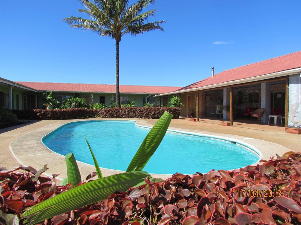 uma piscina em frente a um edifício com uma palmeira em Hotel Manutara em Hanga Roa