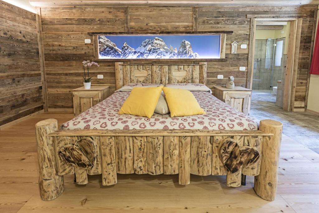 een slaapkamer met een bed en een tv aan de muur bij Agriturismo Alle Baite in Branzi