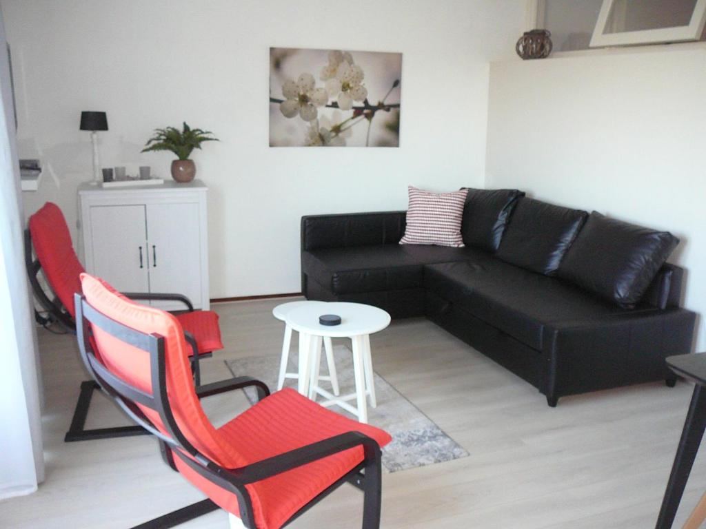 - un salon avec un canapé noir et des fauteuils rouges dans l'établissement Strandslag Zanddijk 149 Julianadorp aan Zee, à Julianadorp