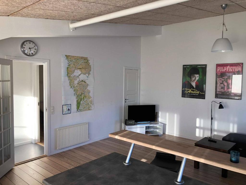 uma sala de estar com uma mesa e um relógio na parede em Kang Apartment em Nuuk