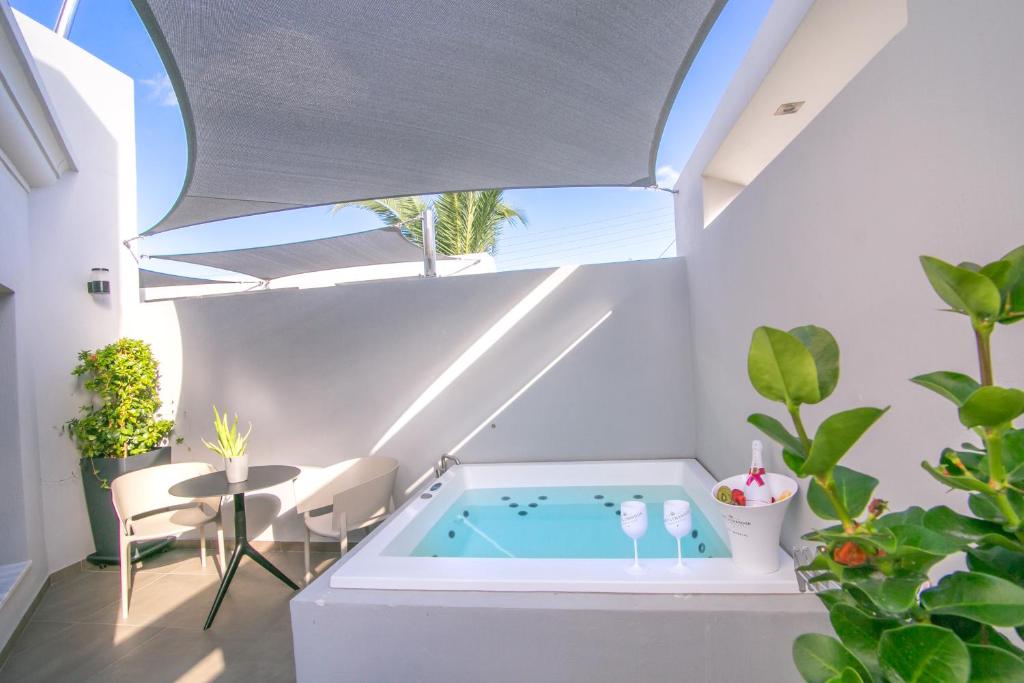 bañera de hidromasaje cubierta en una habitación con ventana en Marquise Suites - Adults Only, en Fira