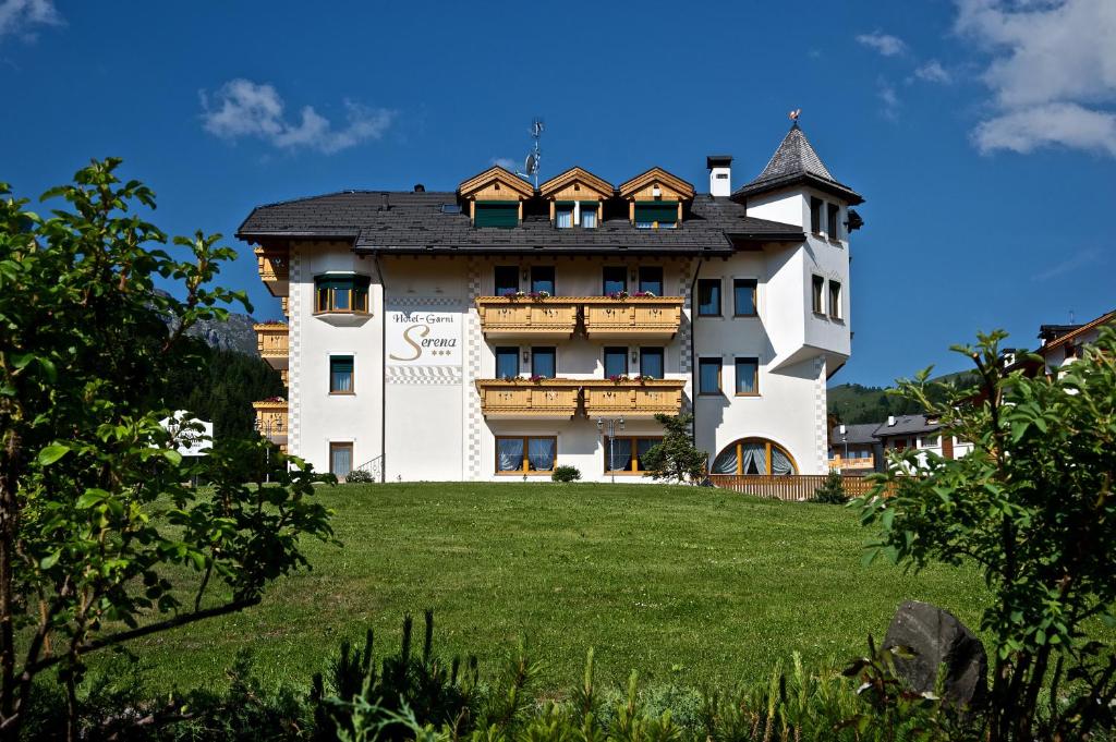 un gran edificio blanco en lo alto de un campo verde en B&B Garni Serena, en Arabba