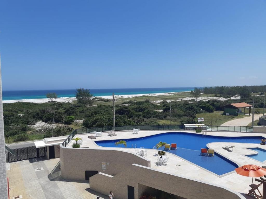 una gran piscina con la playa en el fondo en Le Bon Vivant Residential, en Arraial do Cabo