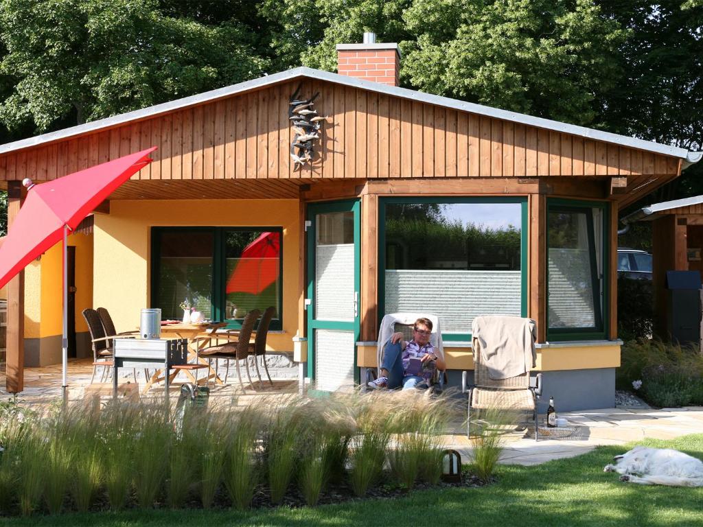 a woman sitting in a chair in front of a house at Ferienhaus H.Winkler in Neukalen