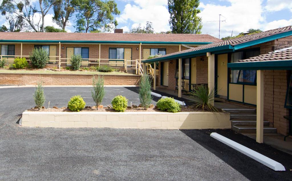 a parking lot in front of a building with plants at Hideaway Motor Inn in Armidale