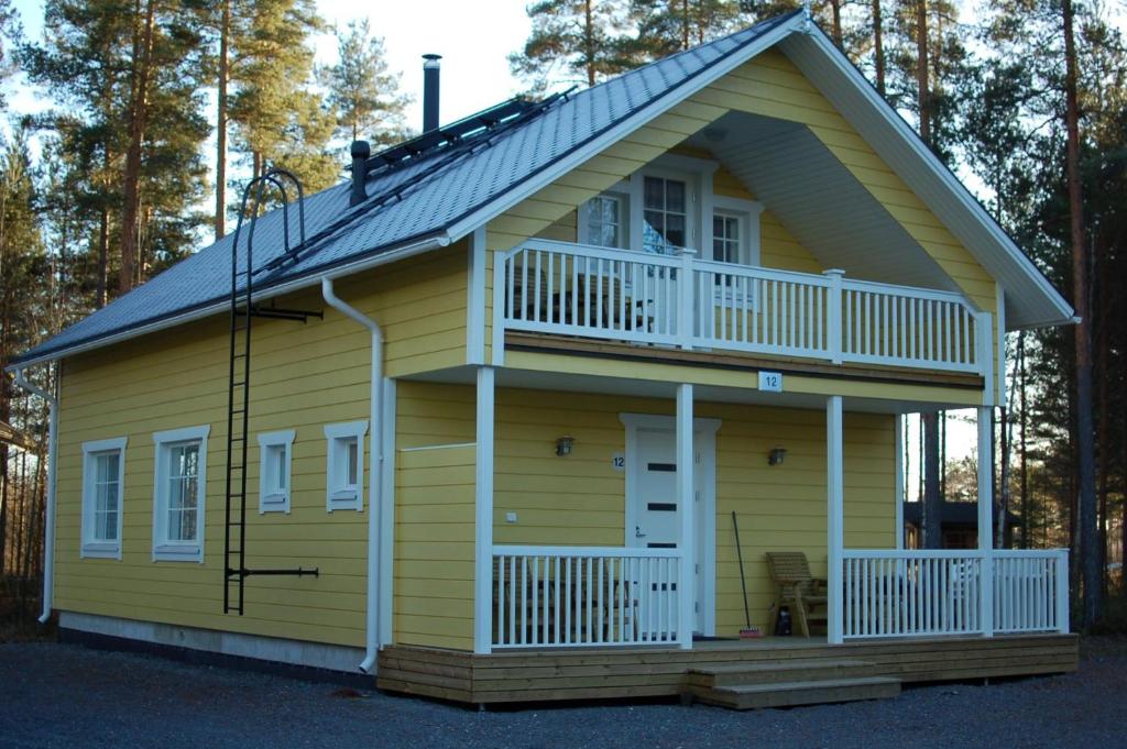 a yellow tiny house with a porch and a balcony at Aurinkolinna 12 in Peräseinäjoki