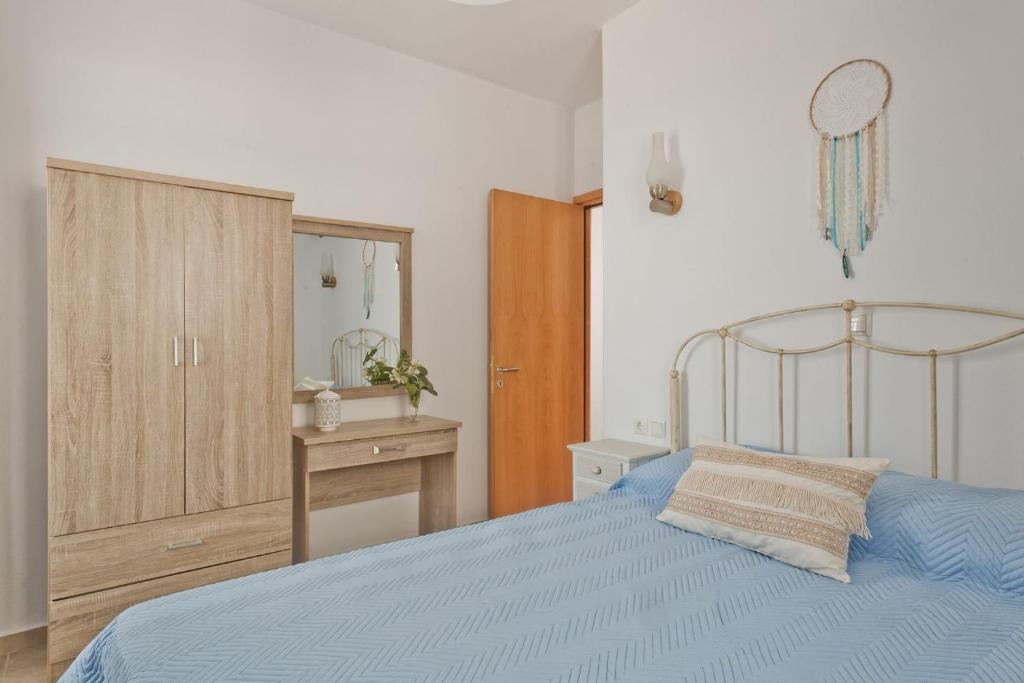 a bedroom with a blue bed and a wooden cabinet at Alisachni Villas in Lefkos Karpathou