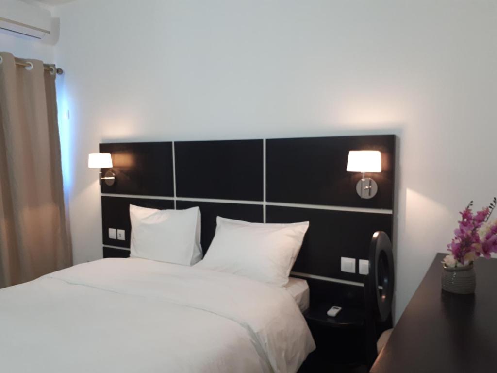 1 dormitorio con 1 cama grande con almohadas blancas en hôtel sainte emmanuelle, en Soubré
