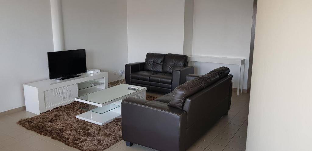 sala de estar con 2 sillas de cuero y TV en Hello Guyane 6, Appartement, Haut Standing, en Cayenne