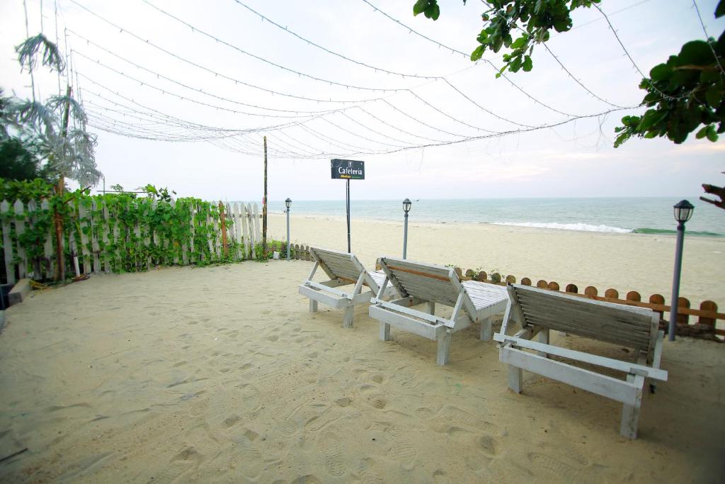 three benches sitting on a beach near the ocean at Shalom Beach Residency in Alleppey