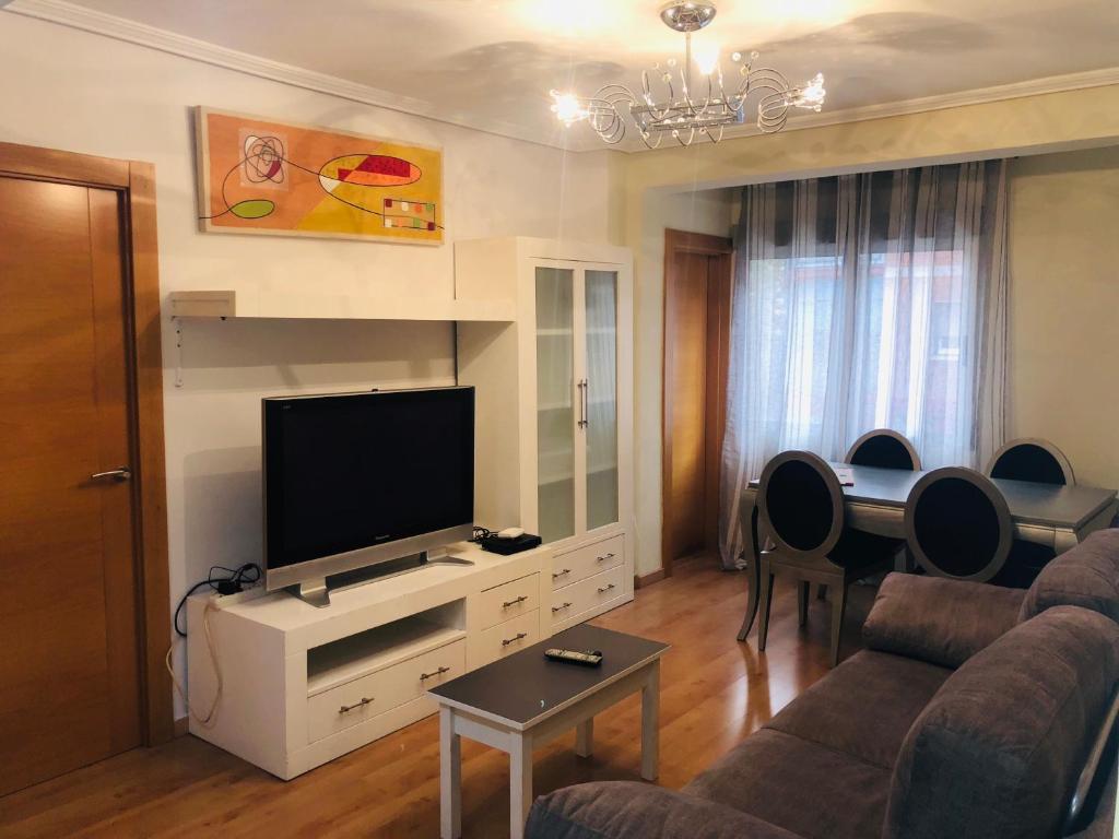 uma sala de estar com uma televisão, um sofá e uma mesa em Piso Avenida de Madrid em Zaragoza