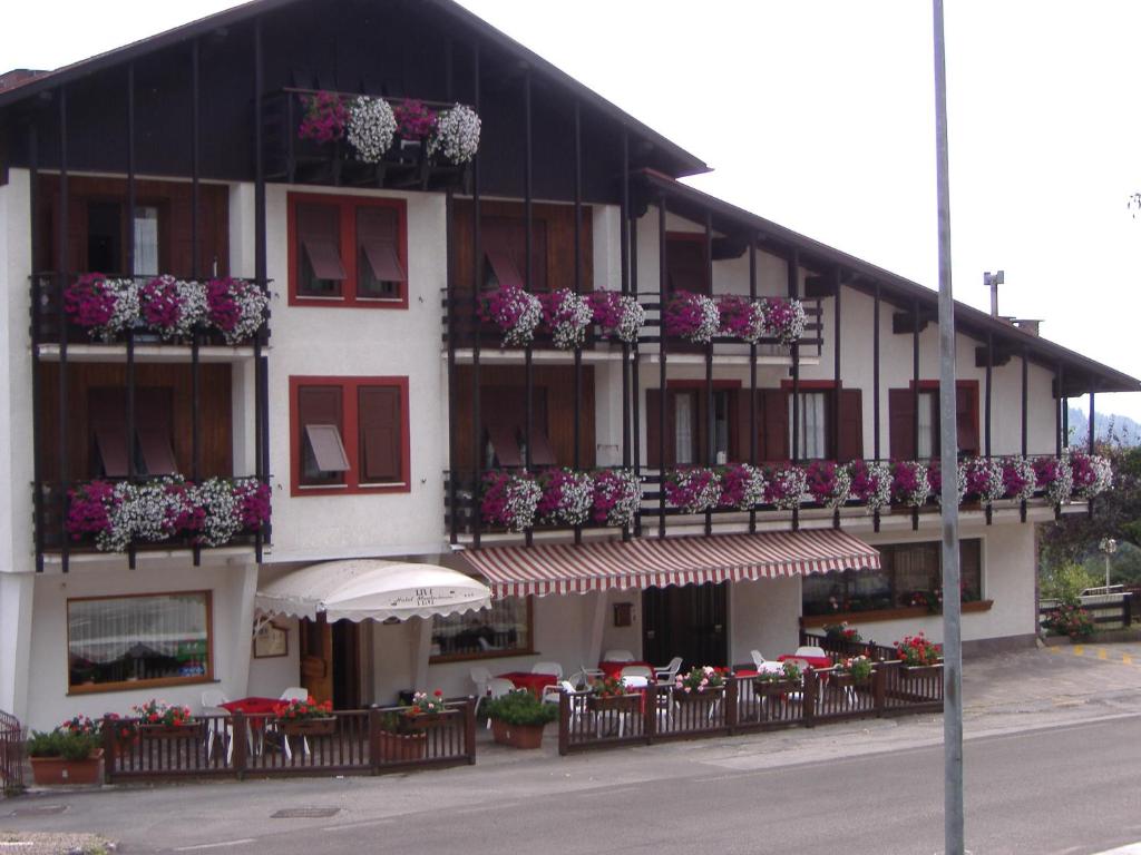 - un bâtiment avec des fleurs sur les balcons et les tables dans l'établissement Residence Hotel Montechiara, à Baselga di Pinè