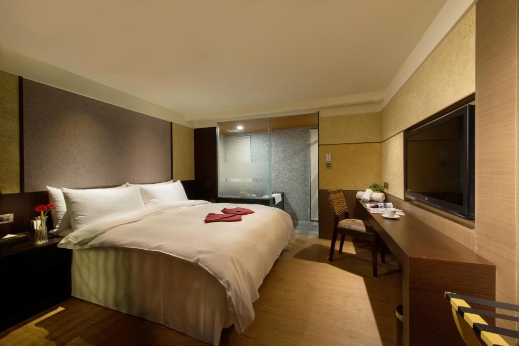 a bedroom with a bed and a desk and a television at Beitou Hot Spring Resort in Taipei