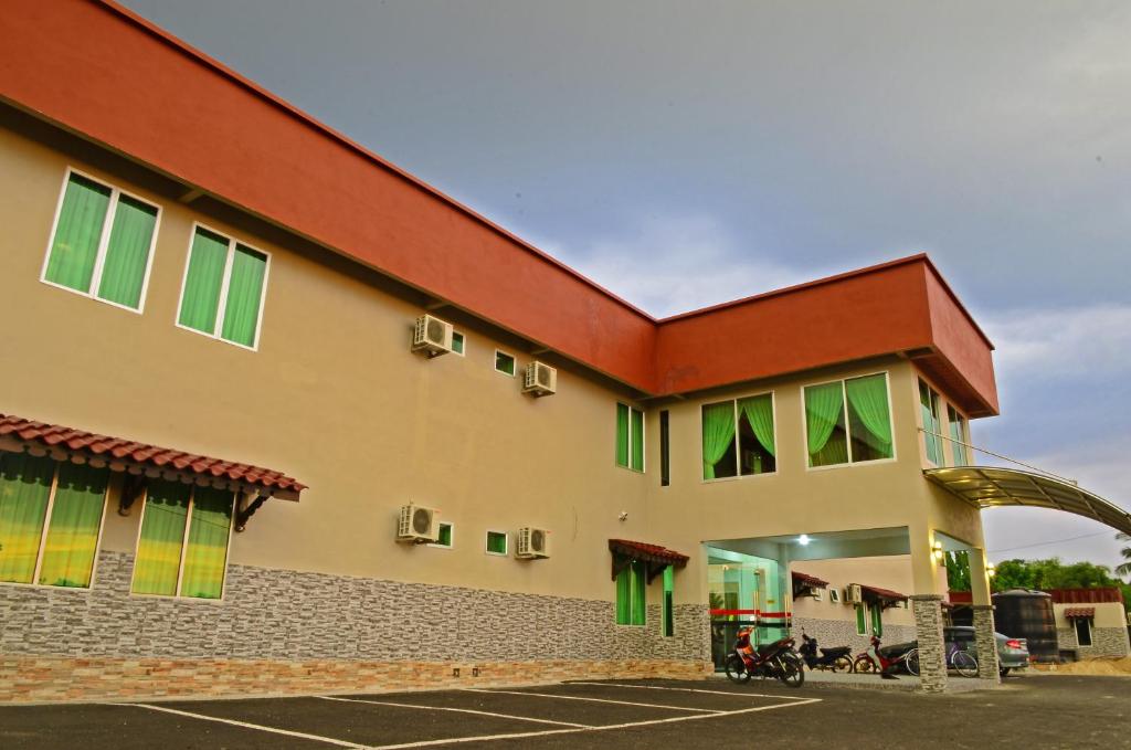 a building with green windows and a parking lot at HOTEL MESRA ALOR SETAR in Alor Setar
