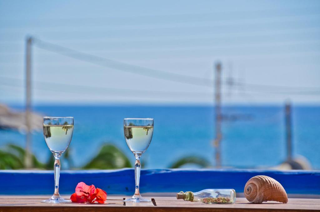 two glasses of wine sitting on a table near the ocean at Sea View Apartments & Studios in Agia Anna Naxos