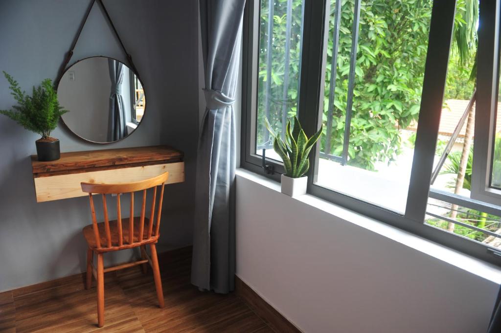 espejo y silla en una habitación con ventanas en Hue Sweethouse 2 Homestay en Hue