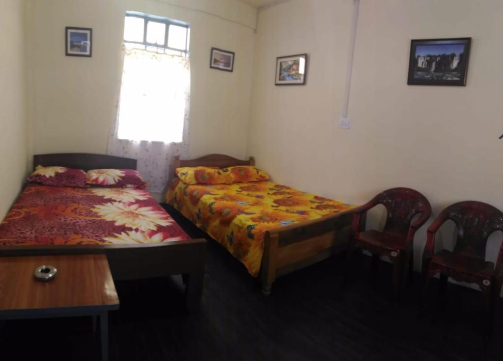 a bedroom with two beds and a table and chairs at Goshen homestay in Cherrapunji