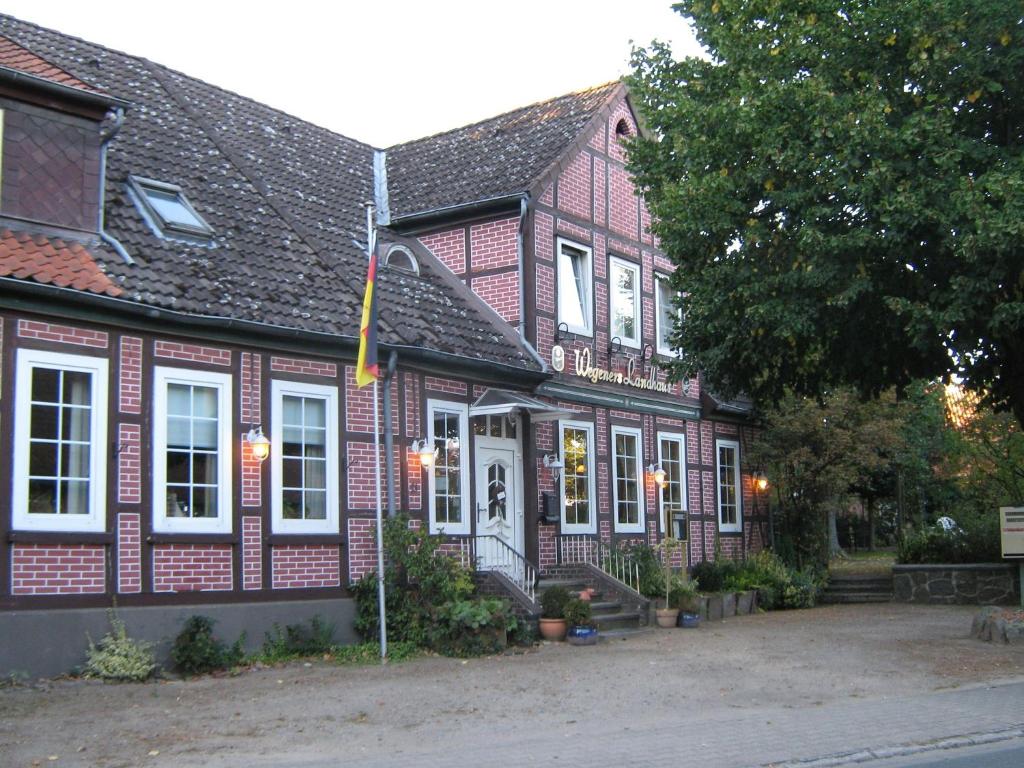 Wegeners Landhaus UG في أويلتسن: منزل من الطوب الأحمر مع نوافذ بيضاء وشرفة