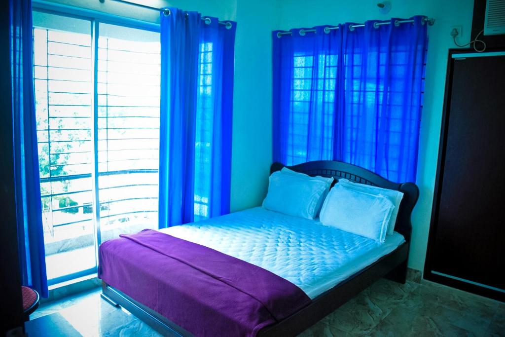 1 dormitorio con 1 cama con paredes y ventanas azules en Saanha Windtrip en Sylhet