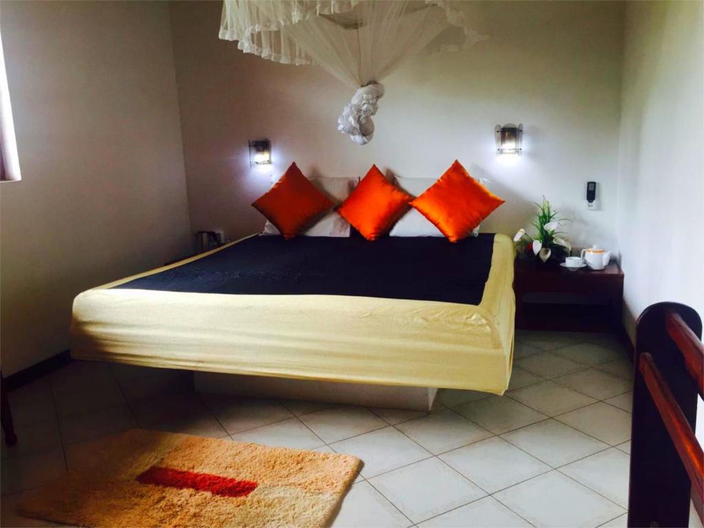 1 dormitorio con 1 cama con almohadas de color naranja y negro en Chaya Villa Guest House, en Beruwala