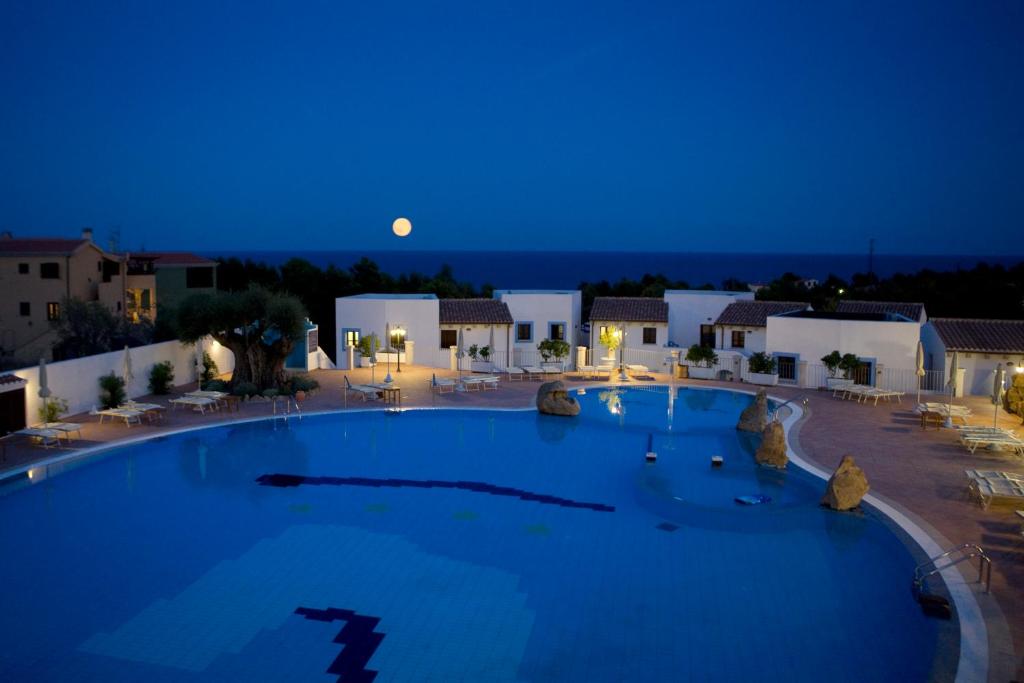 a large swimming pool at night with the moon in the background at Hotel Nuraghe Arvu in Cala Gonone