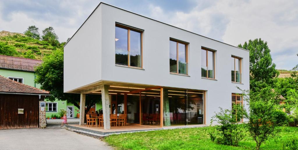 een wit huis met glazen deuren en ramen bij Ferienwohnung am Weingut Eisenbock in Strass