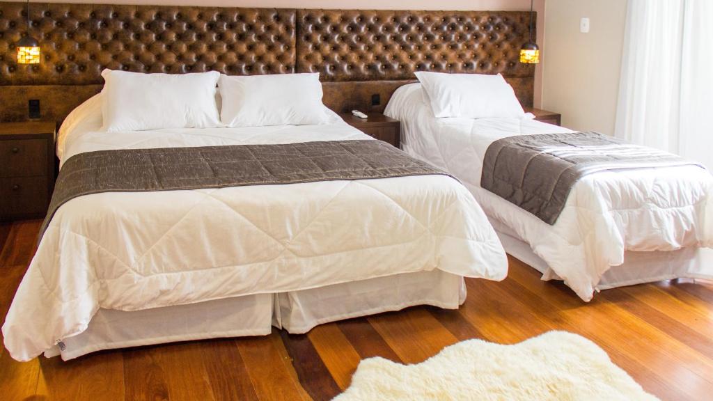 
two beds with pillows and pillows in a room at Tri Pousada Caracol in Canela
