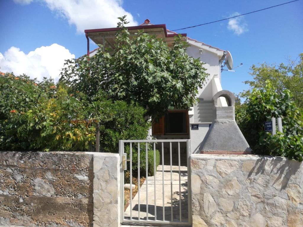 a small white house with a gate and trees at Guest House Dobriša in Vinišće